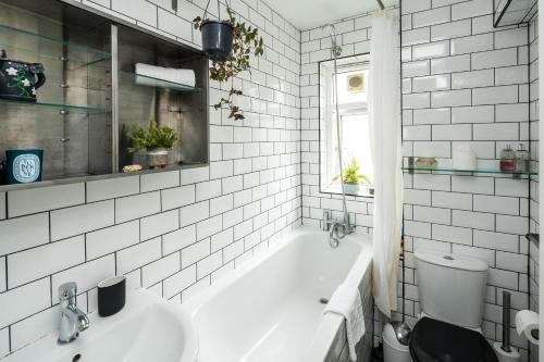 a white bathroom with a tub and a toilet at 2BD Stylish Home w/t Grand Piano Central London in London