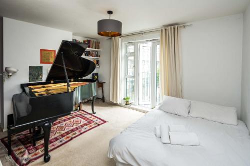 a bedroom with a bed and a piano at 2BD Stylish Home w/t Grand Piano Central London in London