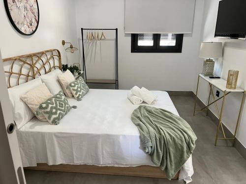 a bedroom with a large white bed with pillows at Apartamentos La Chimenea in Mérida