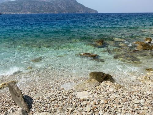 a rocky beach with blue water and rocks at Dolphin Hotel Apartments in Karpathos Town