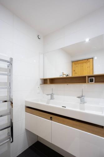 une salle de bain blanche avec deux lavabos et un miroir dans l'établissement Chalet Ozzy, à Oz