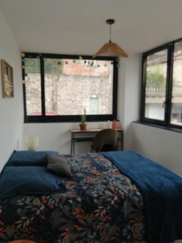 une chambre avec un lit et un bureau et deux fenêtres dans l'établissement Apptt rénové bien situé parking terrasse vélos, à Blois