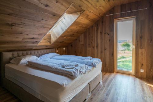 Cette chambre en bois comprend un grand lit et une fenêtre. dans l'établissement Unique Lipno Apartment, à Černá v Pošumaví