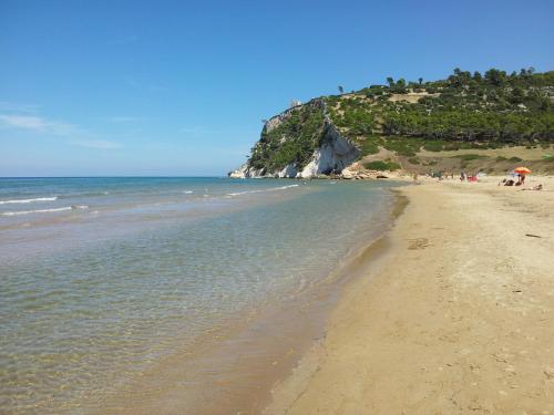 a beach with people and the ocean on a sunny day at Case Vacanza Al Borgo Antico in Vico del Gargano
