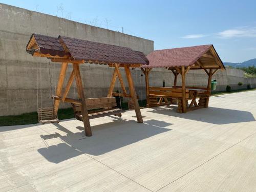 two wooden gazebos sitting next to a wall at Hotel Maya in Horezu