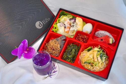 a lunch box with noodles and vegetables next to a laptop at D Eco Wellness Center in North Pattaya