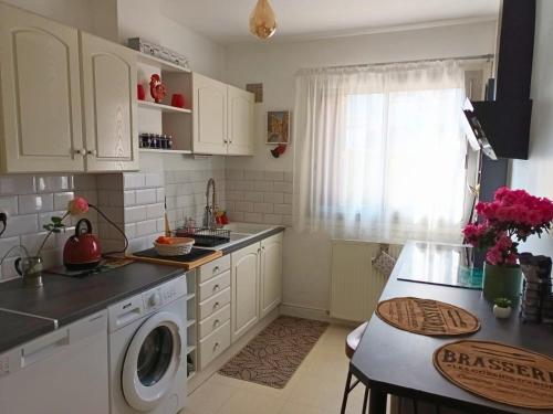 une cuisine avec des armoires blanches et une machine à laver dans l'établissement JARDIN BOTANIC, à Bayeux