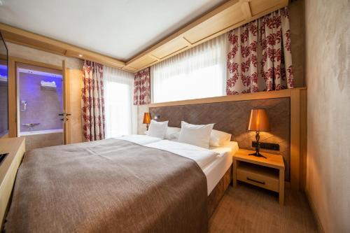 a hotel room with a large bed and a window at Hotel Alpina deluxe in Obergurgl