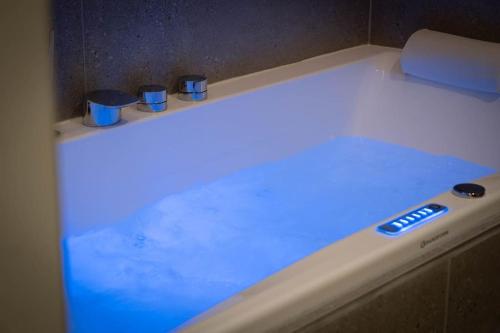 eine weiße Badewanne mit blauem Licht in der Unterkunft Villa La Roseraie in Vichy
