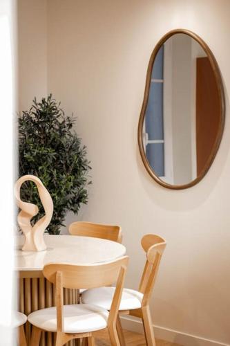 a table and chairs with a mirror on the wall at Villa La Roseraie in Vichy
