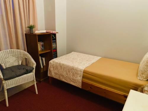 a bedroom with a bed and a chair and a book shelf at Homey Family ArtAki in Néa Artáki
