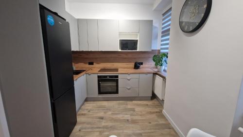 La cuisine est équipée de placards blancs et d'un réfrigérateur noir. dans l'établissement Apartament Przy Dworcu (centrum), à Tarnowskie Góry