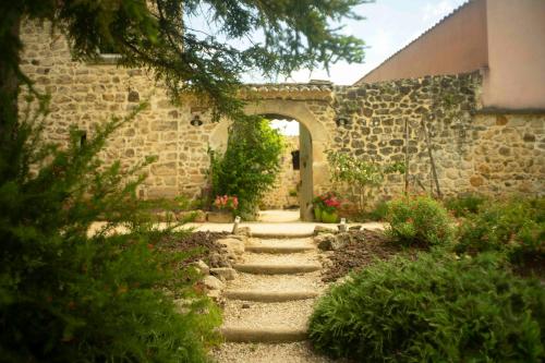 un jardin avec un chemin en pierre menant à un bâtiment dans l'établissement Mas Héritage, 1455 route de Balbiac, à Rosières
