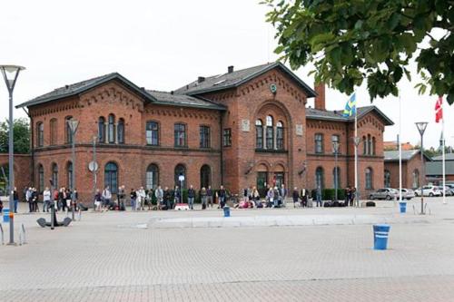 un grand bâtiment en briques avec des personnes devant lui dans l'établissement Stationen, à Ystad