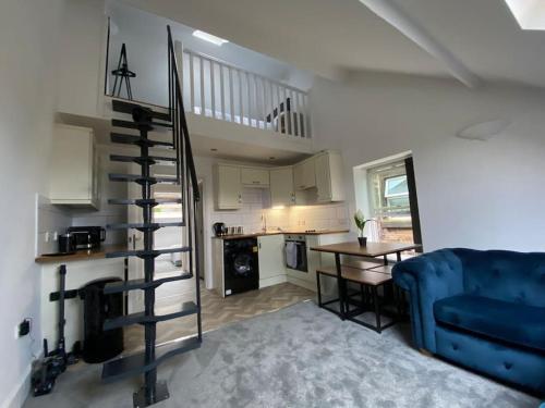 sala de estar con sofá azul y escalera de caracol en Wards House Loft Apartment, Matlock, en Matlock