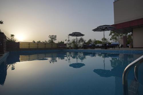 a swimming pool with two umbrellas on the side at Hotel Atulyaa Taj in Agra