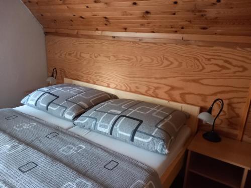 a bed in a room with a wooden wall at Chata Bohouš in Petrovice