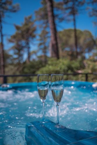 two wine glasses sitting on a table next to a swimming pool at Villa Cesi Resort & Spa in Impruneta