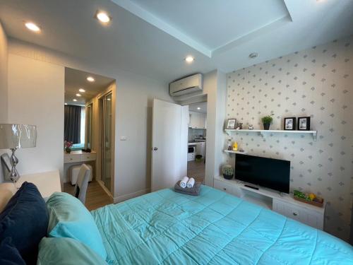 a bedroom with a blue bed and a television at The Blu X Condo Bangsean R9 in Ban Bang Saen (1)