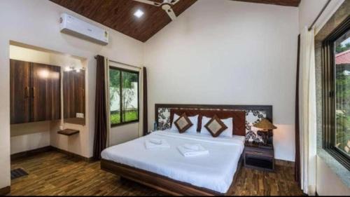 a bedroom with a large bed and a window at Tiara Resort Mandwa in Alibaug