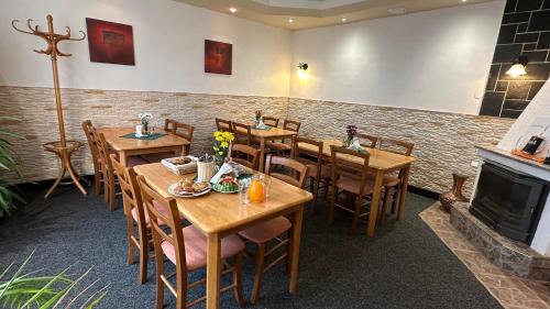 restauracja z drewnianymi stołami i krzesłami oraz kominkiem w obiekcie Penzion u Fouska w mieście Chodov