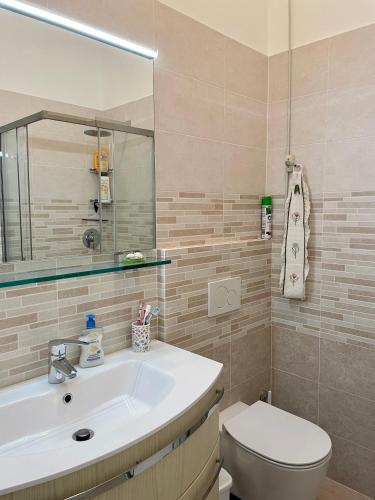 bagno con lavandino, servizi igienici e specchio di Residenza Mayla a Lignano Sabbiadoro