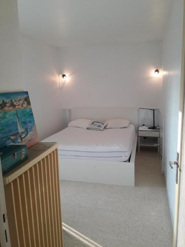 - une petite chambre avec un lit blanc et une table dans l'établissement Joli appt 2 chambres et studio avec parking dans résidence ombragée et calme 5mns plage et commerces, au Grau-du-Roi