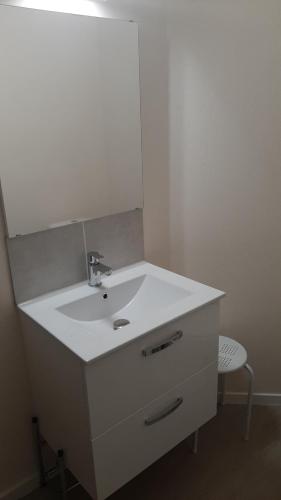 une salle de bain avec un lavabo blanc et une chaise dans l'établissement Joli appt 2 chambres et studio avec parking dans résidence ombragée et calme 5mns plage et commerces, au Grau-du-Roi