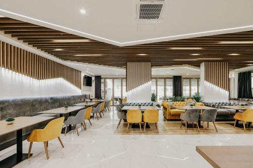 - une salle à manger avec des tables, des chaises et des fenêtres dans l'établissement SPA Hotel Green Park, à Garmen