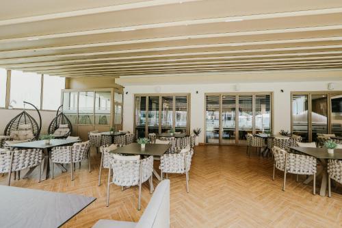 a dining room with tables and chairs and windows at Hotel Green Park Service Perfected in Garmen