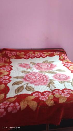 uma cama com um cobertor vermelho com flores em Shivangari Home Stay By WB Homes em Mandāli