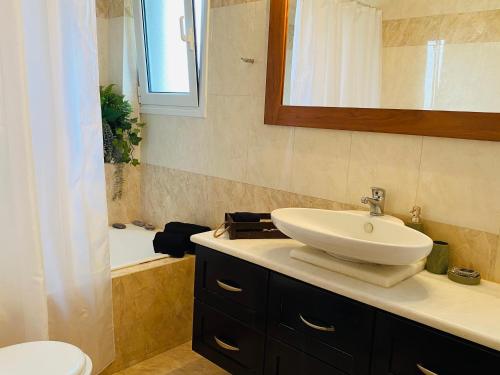 een badkamer met een wastafel, een toilet en een bad bij Homey Family ArtAki in Nea Artaki