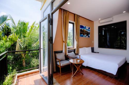 a bedroom with a bed and a chair and a balcony at Lancelynk Retreat Hoi An in Hoi An