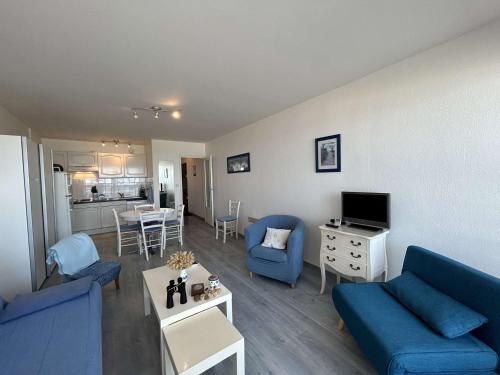un salon avec des canapés bleus et une cuisine dans l'établissement Appartement rénové 3 pièces, vue mer, accès direct plage, parking privé, 4 couchages - FR-1-224C-89, à Saint-Jean-de-Monts
