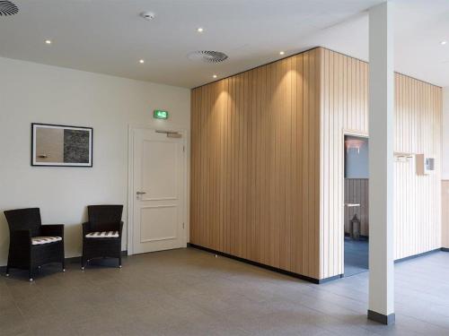 a conference room with two chairs and a wooden wall at Hotel Gut Kaden in Alveslohe