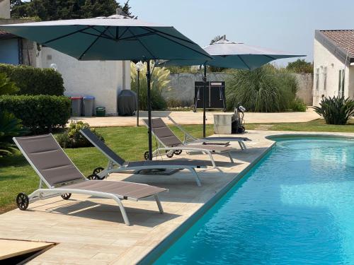 a group of chairs and umbrellas next to a pool at Villa mare Fontane Bianche in Fontane Bianche
