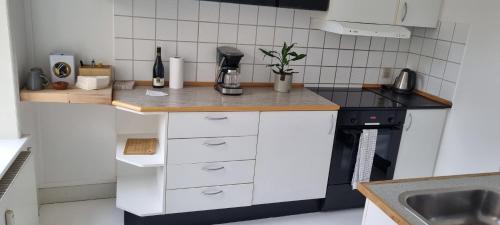 una pequeña cocina con armarios blancos y estufa negra en Gueens Palace, en Svendborg