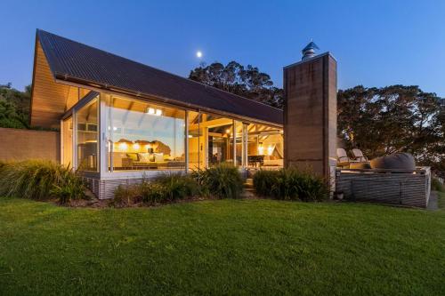 a house with a lot of windows in a yard at The Glasshouse in Whangarei Heads