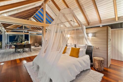 a bedroom with a bed with a mosquito net at The Glasshouse in Whangarei Heads