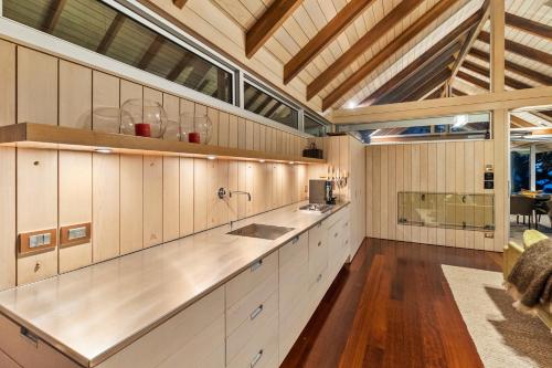uma grande cozinha com armários brancos e piso em madeira em The Glasshouse em Whangarei Heads