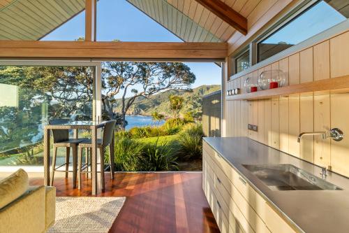 an open kitchen with a view of the water at The Glasshouse in Whangarei Heads