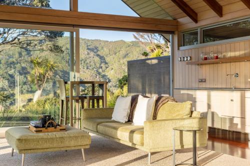 a living room with a couch and a large window at The Glasshouse in Whangarei Heads