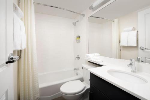 a white bathroom with a toilet and a sink at Candlewood Suites Alexandria West, an IHG Hotel in Alexandria