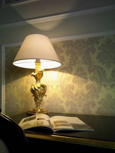 a lamp sitting on a table with an open book at Hotel Villa Del Sogno in Gardone Riviera