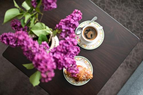 una mesa con una taza de café y flores púrpuras en Vila Vika, en Palanga