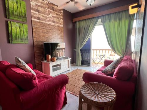 Sala de estar con 2 sofás rojos y TV en Glory beach private PD en Port Dickson