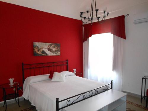Un dormitorio rojo con una cama blanca y una ventana en Mareluna, en Siracusa