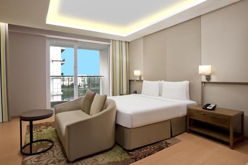 une chambre d'hôtel avec un lit, une chaise et une fenêtre dans l'établissement DoubleTree Suites by Hilton Bengaluru Outer Ring Road, à Bangalore