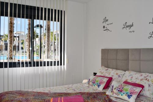 um quarto com uma cama com almofadas cor-de-rosa e uma janela em Casa La Zenia em Playas de Orihuela