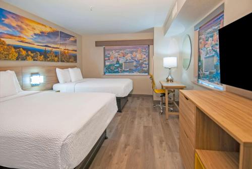 Days Inn & Suites by Wyndham San Antonio North/Stone Oak في سان انطونيو: غرفة فندقية بسريرين وتلفزيون بشاشة مسطحة